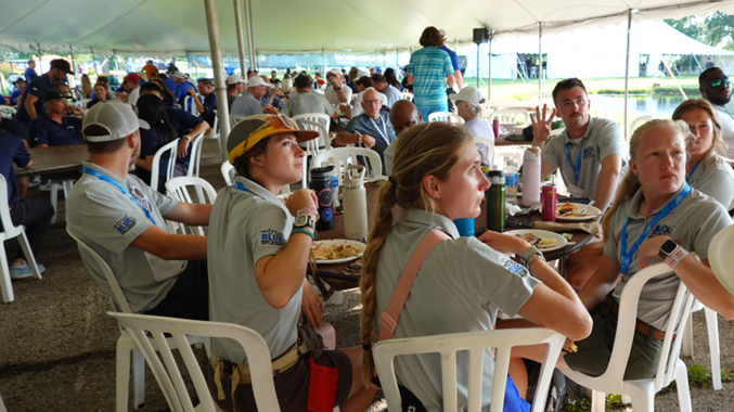 Group of people sitting around a table in the tent.