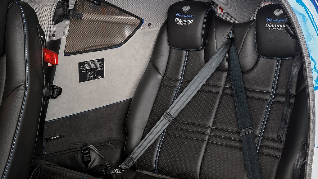A close-up view of the third row of seats in a DA62 aircraft, showcasing luxurious black leather and a safety belt system.